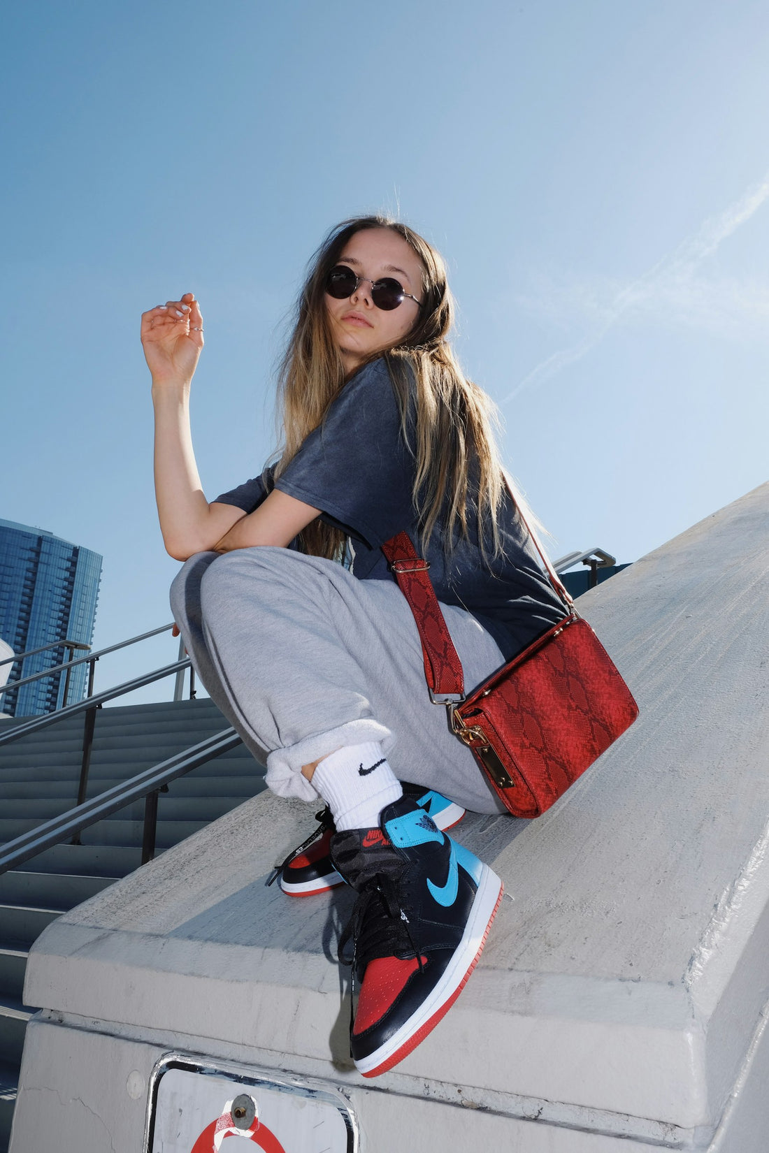 Woman wearing an oversized gray t-shirt sitting on a concrete bench