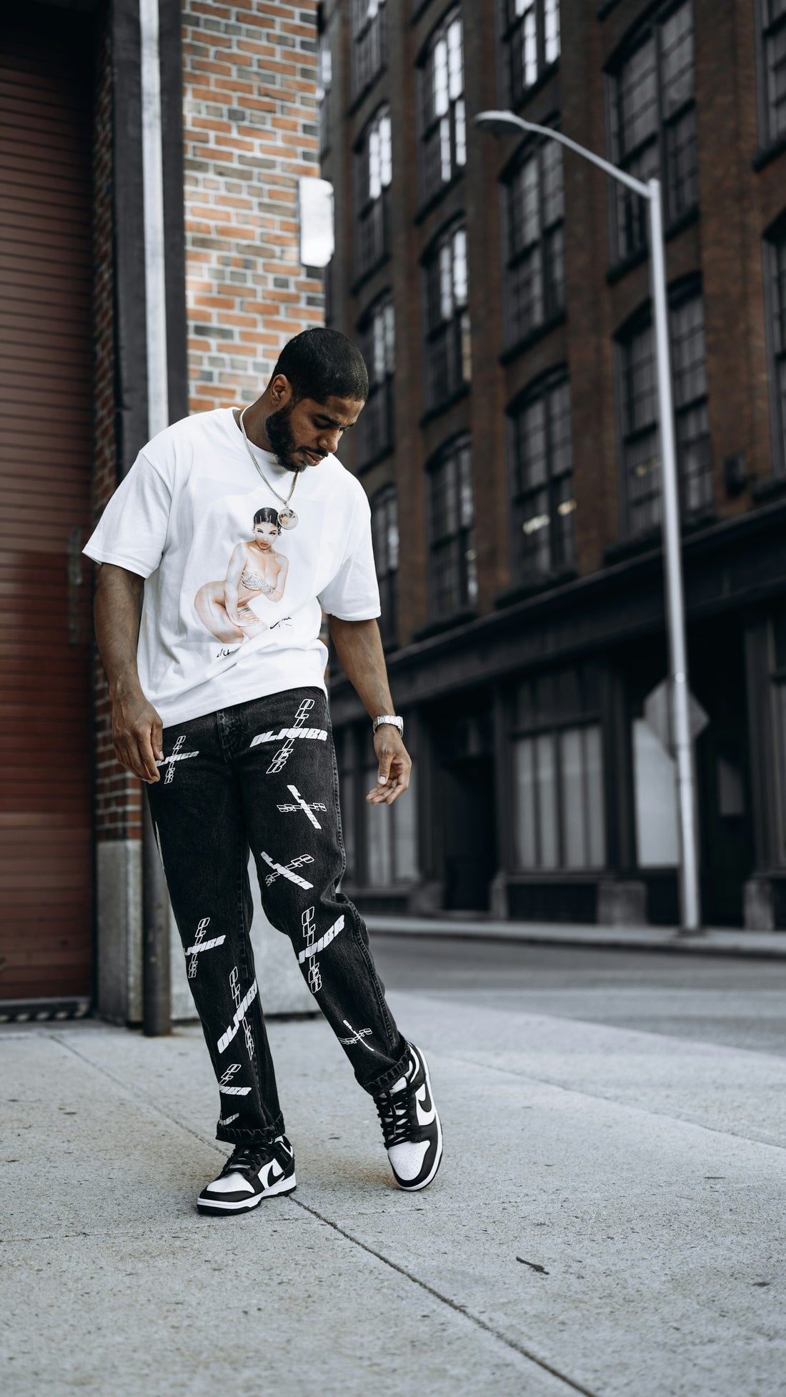 Man wearing a white crew neck t-shirt standing on a sidewalk